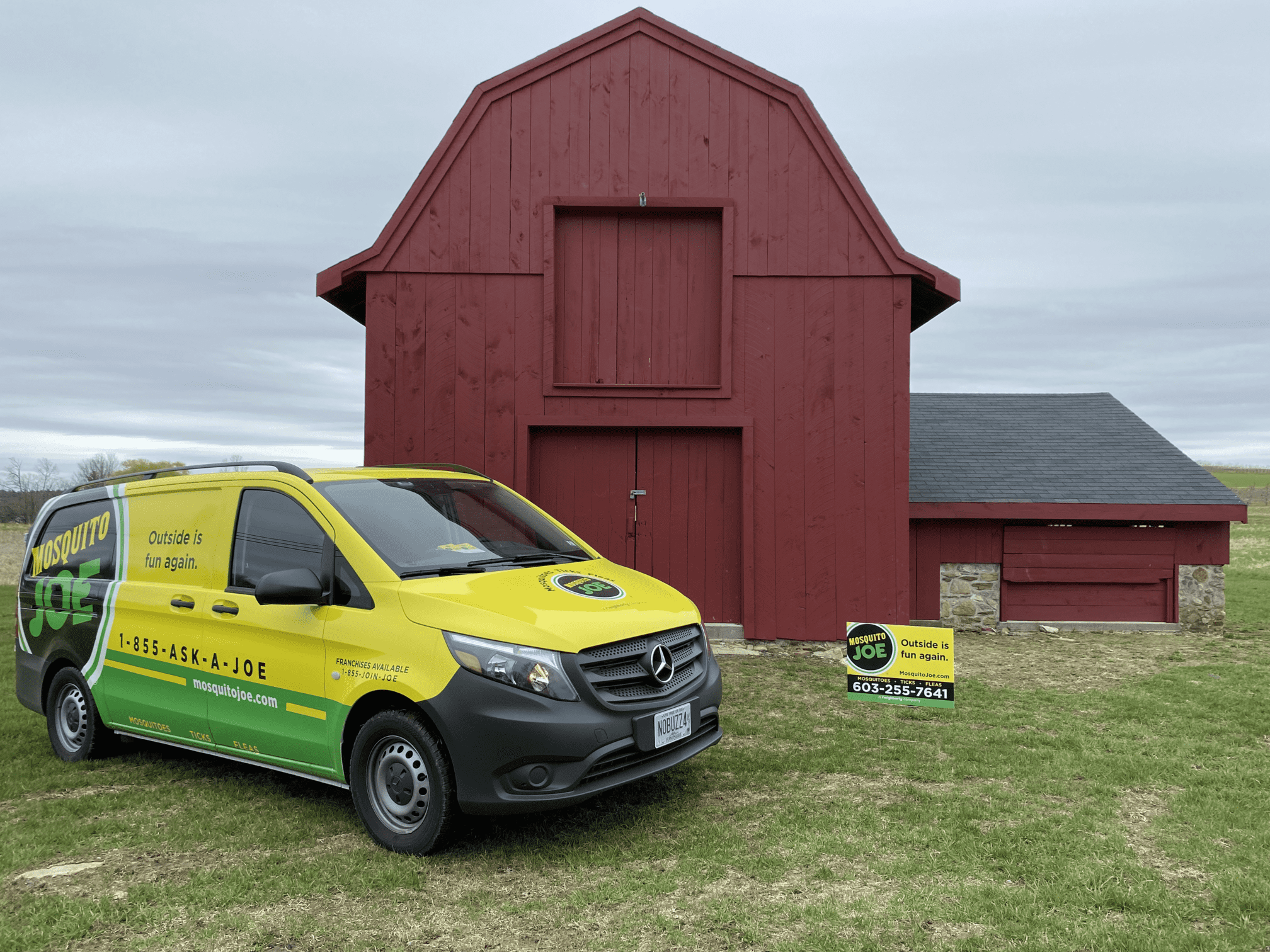 Mosquito Joe of Manchester-Souhegan Valley yellow and green truck and yard sign in front of red barn located in Hollis, New Hampshire. 